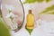 Essential cosmetic flower oil in a glass bottle is opposite the mirror.