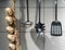 Essential kitchen utensils and decorative artificial garlic chain hanging on hook of metal rail
