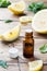 Essential lemon oil in bottle, fresh fruit slices on wooden background. Natural fragrances