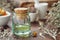 Essential oil bottle, mortars of dry medicinal herbs and old book on background