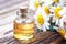 Essential oil in glass bottle with fresh chamomile flowers, beauty treatment. Spa concept. Selective focus.