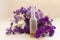 Essential oil in matt bottle on purple flowers blur background.