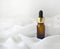 Essential oil or perfume bottle dropper on silk waved background. Minimalist luxury spa aromatherapy or bodycare concept.