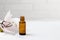 Essential oil or serum cosmetics with white flower on textured white background with copy space top view.