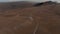 Establishing shot aerial view car driving gravel trail path in Icelandic dusty desert. Drone view 4x4 vehicle speeding