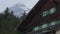 Establishing shot of nice wooden cottage in mountains, snowy rock on background