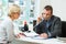 Estate agent in office with client talking on landline