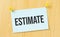 estimate sign written on sticky note pinned on wooden wall