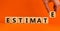 Estimate symbol. Concept word `estimate` on wooden cubes on a beautiful orange background. Male hand. Business and estimate