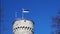 Estonia flag waving on a tall historic tower in Tallinn, Estonia.