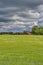 Estonian countryside - green field, cloudy sky and traditional rural house