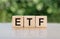 ETF is an abbreviation  exchange-traded fund. Written on wooden blocks. The text is written in black letters and is reflected on