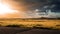 Ethereal scene of a golden field of dried grass illuminated by a vibrant orange and cloudy sunset