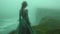 Ethereal Woman in Green Dress Overlooking Foggy Seascape