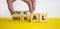 Ethical or moral symbol. Businessman turns wooden cubes and changes the word `moral` to `ethical` on a beautiful yellow table,