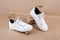 Ethical vegan shoes concept. A pair of white sneakers with dry flowers on the stones against a background of neutral beige craft
