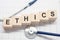 Ethics word written on wooden blocks and stethoscope on light white background