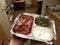 Ethiopian food raw beef, green vegetables, and white cheese in metallic container