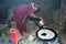 Ethiopian woman with son bakes injera on wood fire