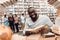 Ethnic african american guy surrounded by books in library. Student is reading book.