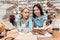 Ethnic asian girl and white girl surrounded by books in library. Students are reading book.