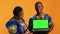 Ethnic couple pointing at laptop with greenscreen display