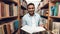 Ethnic indian mixed race student in book aisle of library.