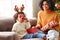 Ethnic mother playing with son in cozy room on Christmas day