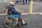 Ethnic old woman sitting on wheelchair holding Christmas gift box begging for alms