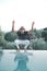 Ethnic Stylish young man splashing water near a swimming pool