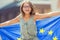 EU Flag. Cute happy girl with the flag of the European Union. Young teenage girl waving with the European Union flag in the city