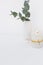 Eucalyptus branch in ceramic vase burning candle on white background, styled image, mockup