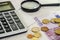 Euro banknote, coins and calculator on a white table.Close-up.