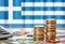 Euro banknotes and coins in front of the national flag of Greece