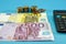 Euro banknotes in denominations of 200 and 500 euros, calculator and coins on blue. Financial concept. Concept of savings or econo