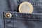 Euro coin with a denomination of one euro in the pocket of dark blue denim jeans