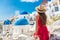 Europe holiday Santorini vacation girl in hat and red dress enjoying view of 3 blue domes famous tourist attraction in