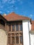 Europe. Part of the old medieval building: the roof covered by red shingles and wooden frame for windows, and white wall of the ho