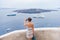 Europe travel tourist woman taking photo with phone of Mediterranean Sea in Santorini, Oia, Greece, with cruise ships