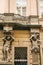 European architecture. Close-up - sculptures - columns in the form of antique characters supporting balcony - facade of