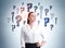 European attractive young woman in white shirt pondering about career opportunities. Question marks drawn on wall behind. Concept