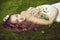 European beautiful pregnant woman in a floral sundress in the summer lies on green grass