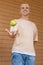 European blond guy tossing a green apple and catching it with his hand, looking at the camera