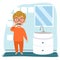 A European boy in glasses and pajamas is brushing his teeth in the bathroom