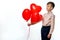 European boy holds three inflatable heart-shaped balloons  a Valentine\'s Day gift  against a white insulated background