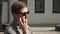 European business man in sunglasses talking on smartphone on urban street