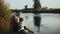 European father and son sit together on lake pier. Boy holds a hand made fishing tackle. Happy family relationships. 4K.