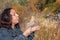 A European girl with black hair blows on a cattail in the hand with which fluff is flying.