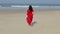 European girl in red saree walks to the Indian Ocean