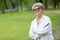 European good-natured retired woman stands in a summer park in a sports suit, copy space